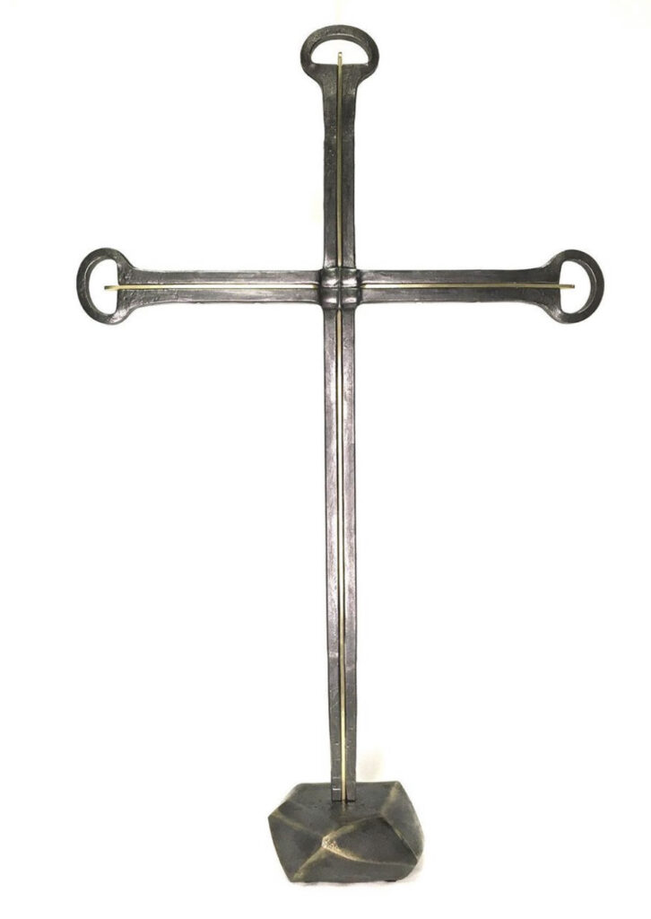 Forged steel and brass cross on a base.