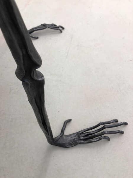 A forged steel arm and hand pressing down on the floor.